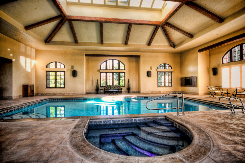 Idee per una grande piscina coperta monocorsia mediterranea rettangolare con pavimentazioni in pietra naturale e una vasca idromassaggio