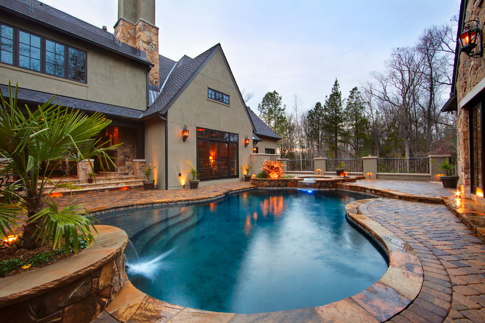 Inspiration for a traditional custom shaped swimming pool in Charlotte with brick paving.