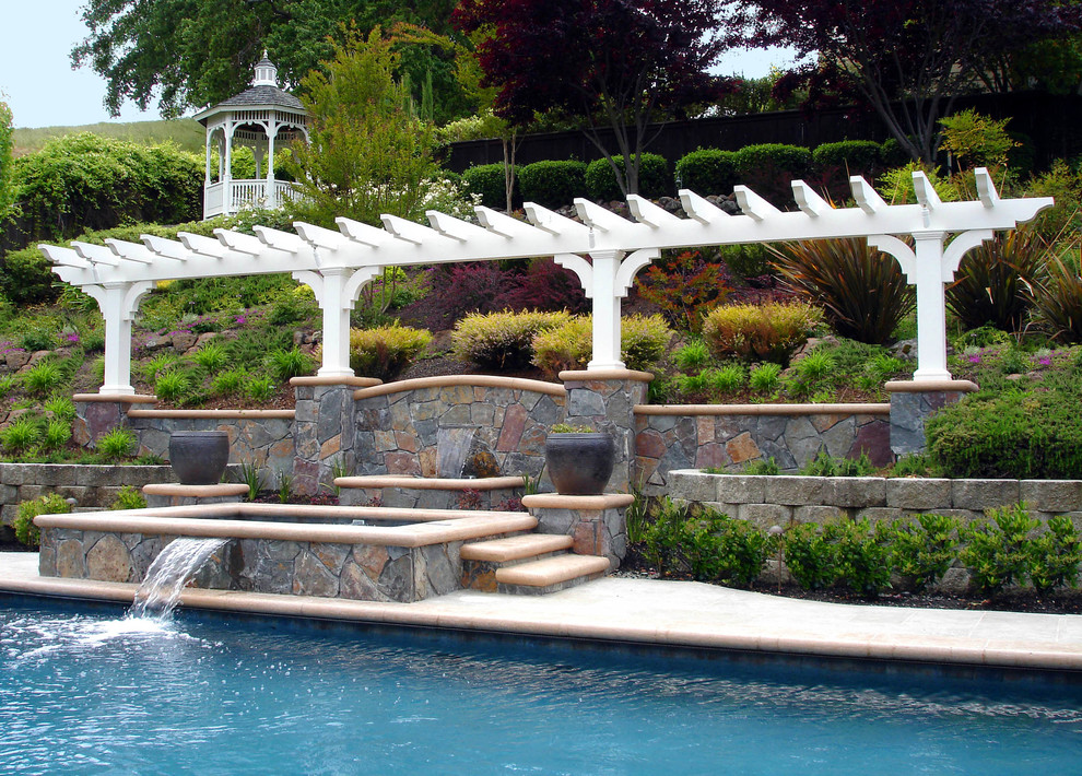 Foto de piscina natural clásica grande a medida en patio trasero con losas de hormigón