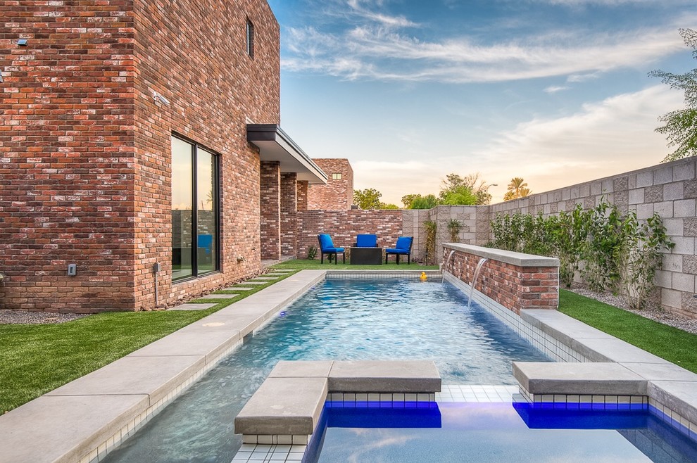 Imagen de piscina con fuente minimalista pequeña rectangular en patio lateral con losas de hormigón