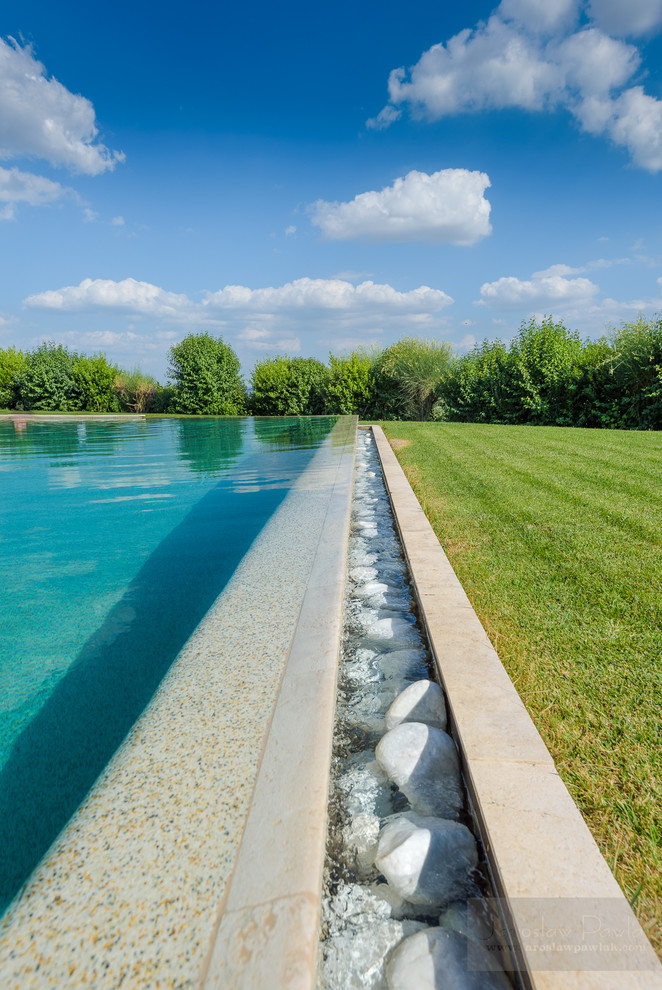 Immagine di una piscina a sfioro infinito mediterranea rettangolare di medie dimensioni e dietro casa con una dépendance a bordo piscina