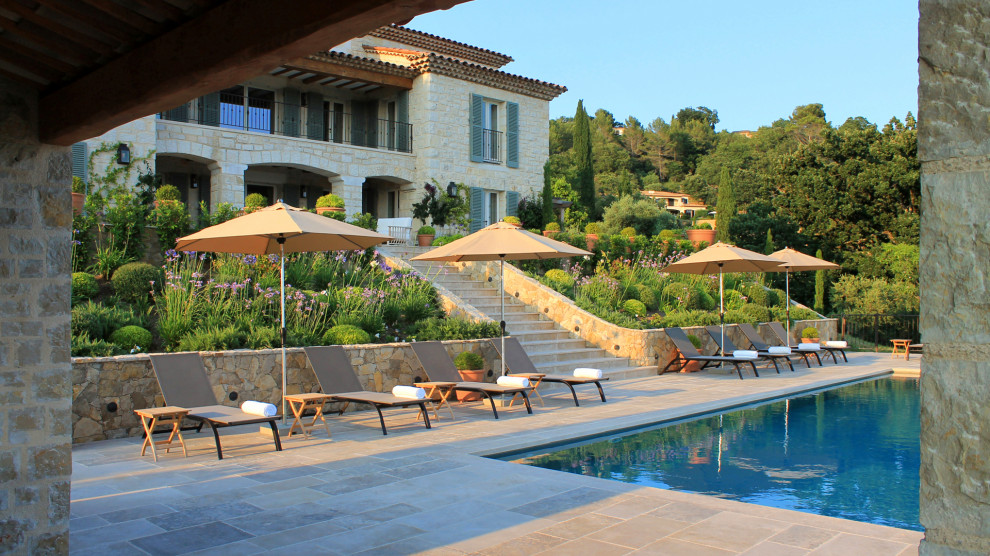 Inspiration for a mediterranean rectangular infinity swimming pool in Nice with natural stone paving.