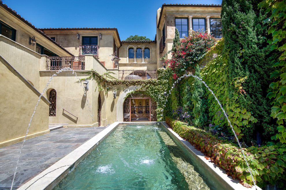 Ejemplo de piscina con fuente alargada mediterránea rectangular en patio con suelo de baldosas