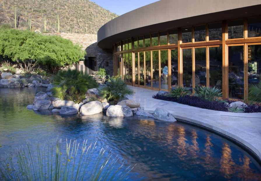Bild på en mycket stor funkis anpassad pool, med en fontän och naturstensplattor