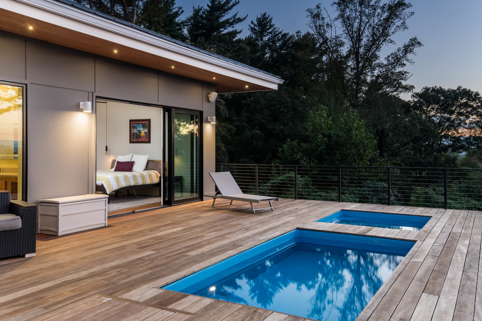 Exemple d'une piscine scandinave rectangle avec un bain bouillonnant et une terrasse en bois.