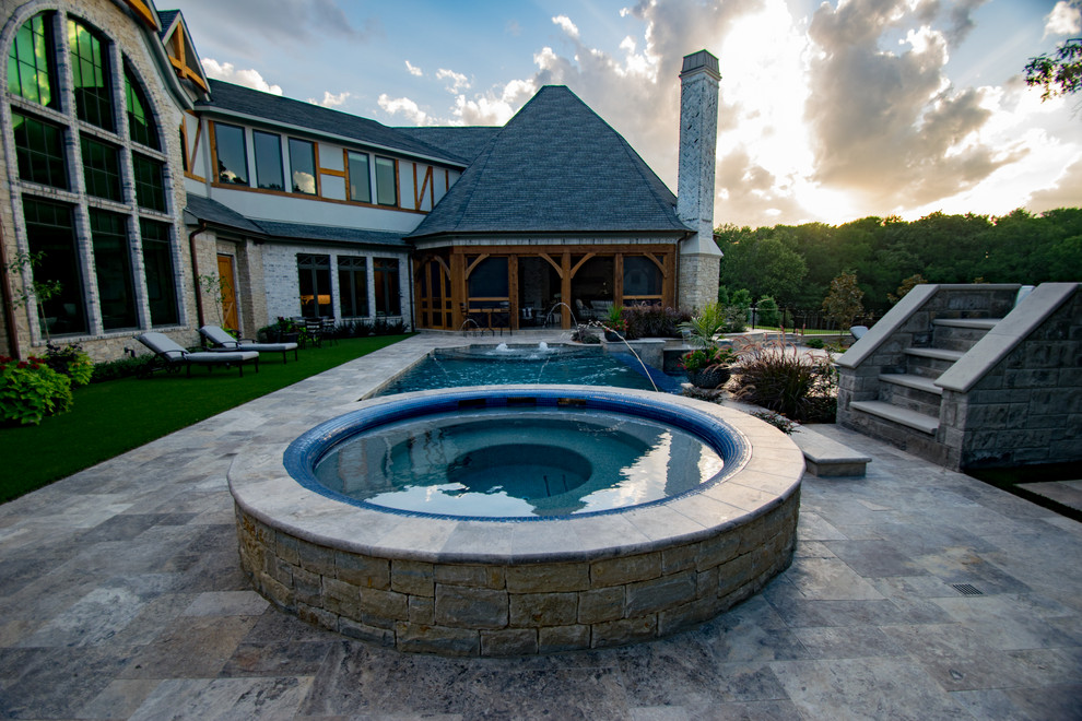 Modelo de piscina con tobogán infinita tradicional grande a medida en patio trasero con adoquines de piedra natural