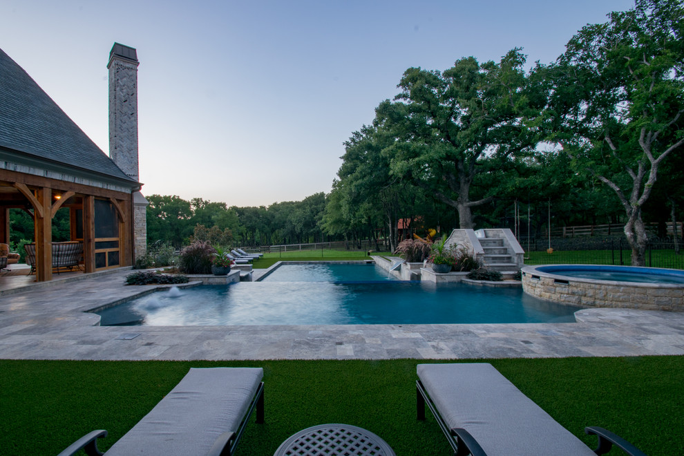 Immagine di una grande piscina a sfioro infinito chic personalizzata dietro casa con un acquascivolo e pavimentazioni in pietra naturale