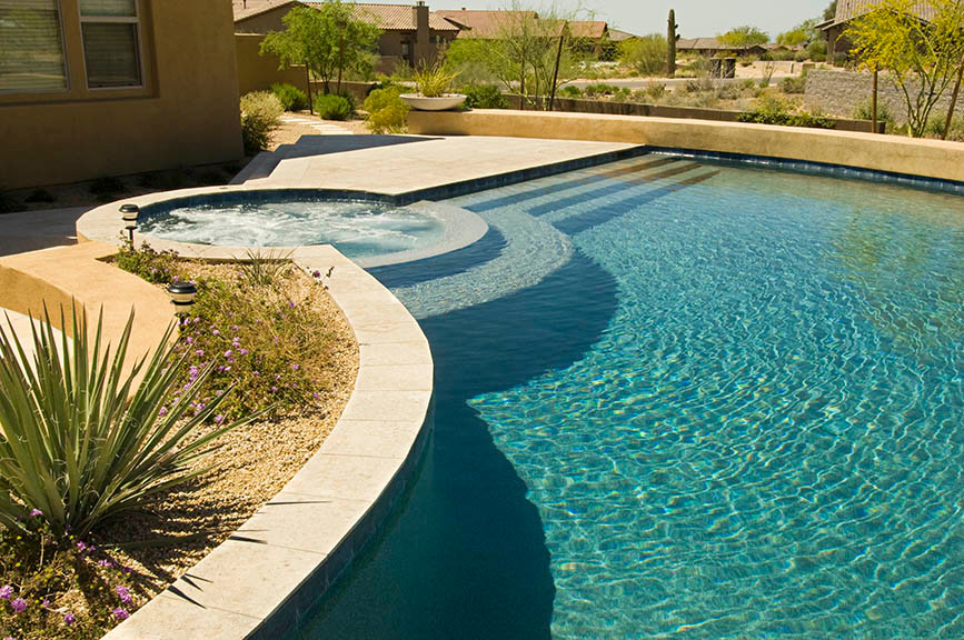 Idee per una grande piscina a sfioro infinito american style personalizzata dietro casa con pavimentazioni in pietra naturale