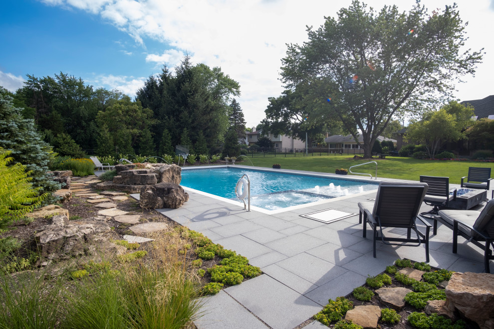 Foto de piscina alargada clásica de tamaño medio rectangular en patio trasero con paisajismo de piscina y adoquines de piedra natural