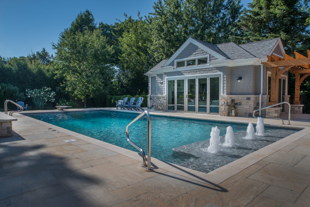 Ejemplo de casa de la piscina y piscina alargada tradicional de tamaño medio rectangular en patio trasero con adoquines de hormigón