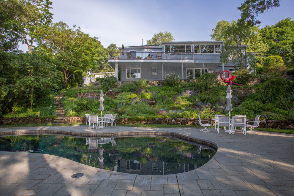 Diseño de piscina clásica renovada tipo riñón en patio trasero con suelo de hormigón estampado