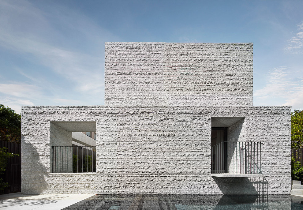 Esempio di una grande piscina monocorsia minimalista rettangolare dietro casa con una vasca idromassaggio e lastre di cemento
