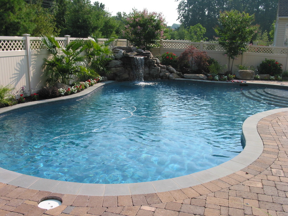 Idee per una piscina naturale classica a "C" di medie dimensioni e dietro casa con fontane e pavimentazioni in cemento