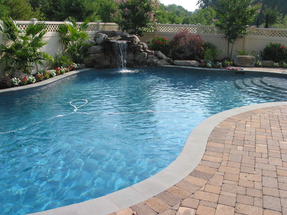 На фото: естественный бассейн среднего размера, в форме фасоли на заднем дворе в классическом стиле с фонтаном и мощением тротуарной плиткой