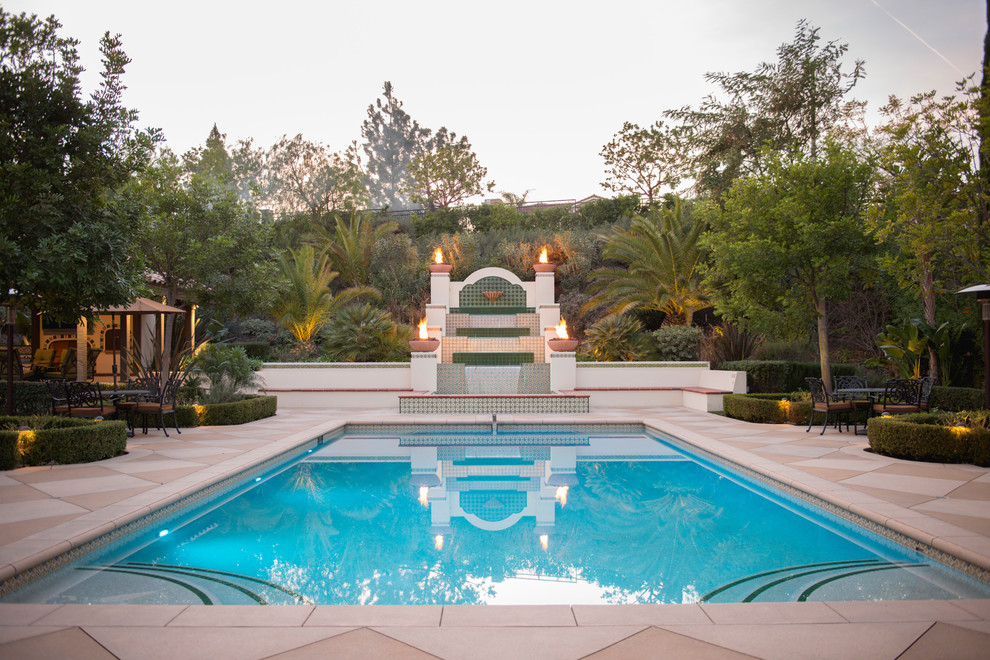Пример оригинального дизайна: большой спортивный, прямоугольный бассейн на заднем дворе в средиземноморском стиле с фонтаном и покрытием из бетонных плит