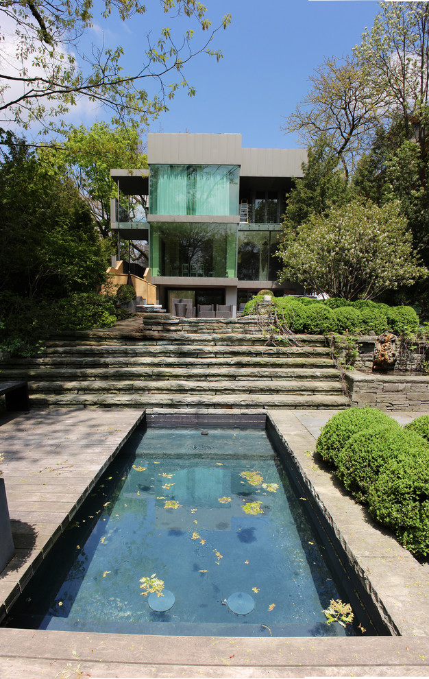 Photo of a contemporary back rectangular lengths swimming pool in Toronto with natural stone paving.