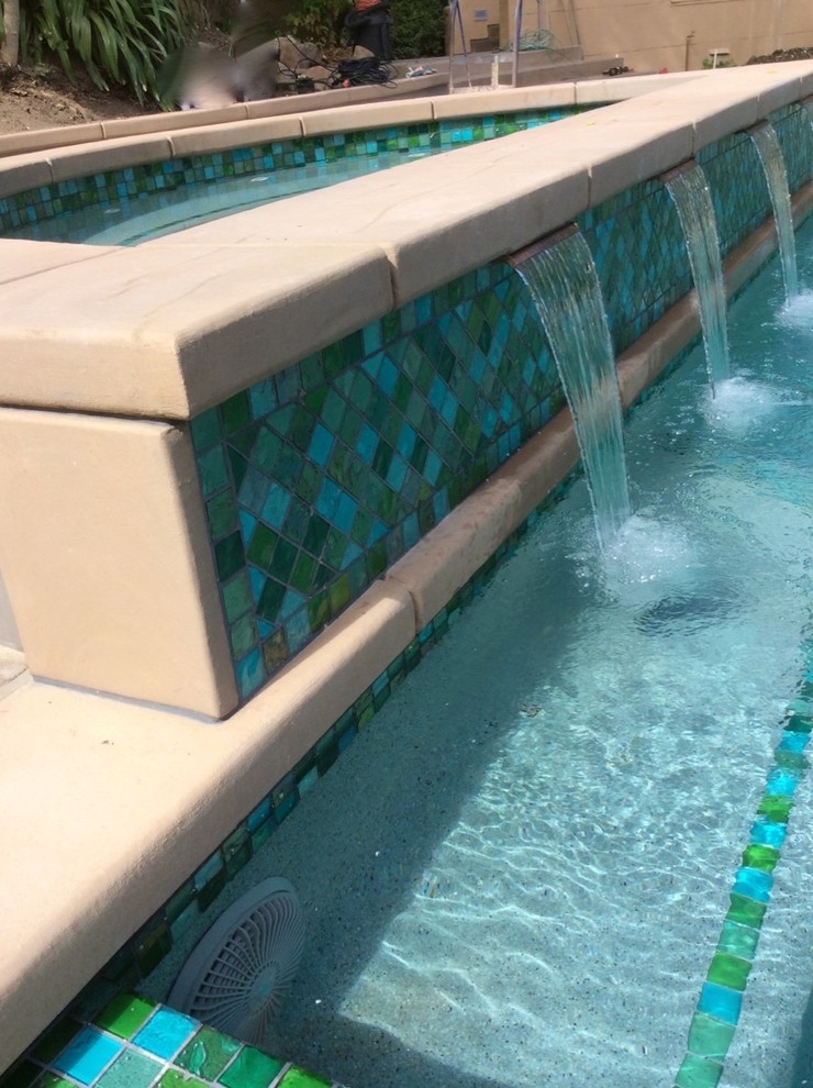 Exemple d'une grande piscine avant tendance rectangle avec un bain bouillonnant et des pavés en béton.