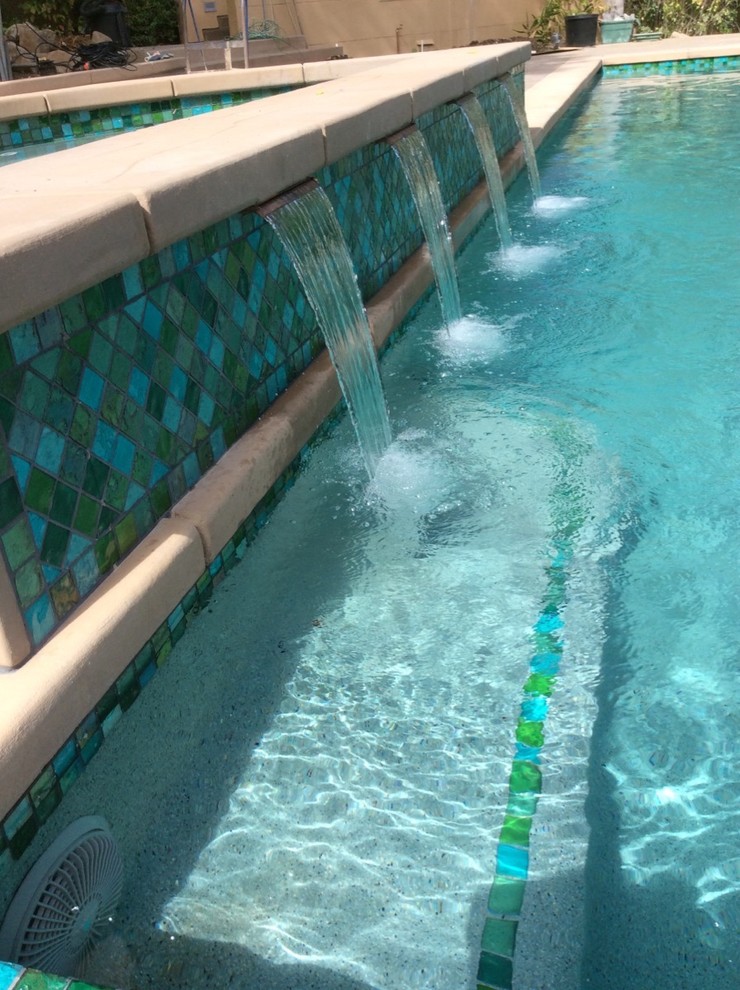 Cette photo montre une grande piscine avant tendance rectangle avec un bain bouillonnant et des pavés en béton.