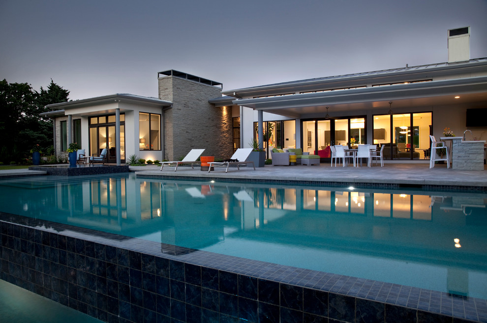 Inspiration pour une grande piscine à débordement et arrière minimaliste rectangle avec un bain bouillonnant et des pavés en béton.