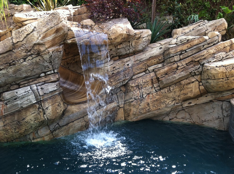 Идея дизайна: естественный бассейн произвольной формы на заднем дворе в стиле рустика с водной горкой