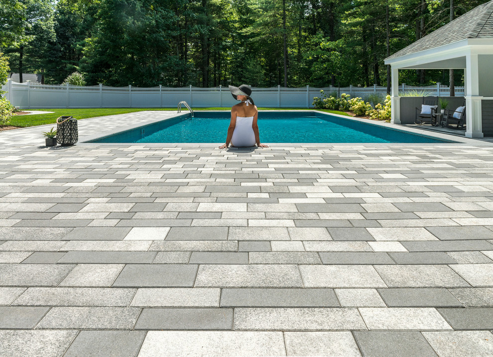 Diseño de piscina alargada contemporánea grande rectangular en patio trasero con adoquines de hormigón