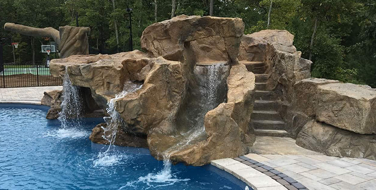 Foto de piscina con tobogán natural tropical grande en patio trasero con adoquines de piedra natural