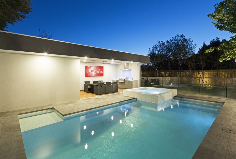 Foto på en mellanstor funkis pool på baksidan av huset, med naturstensplattor