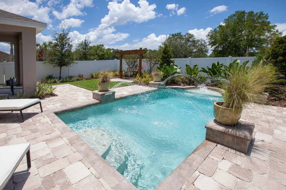 Diseño de piscina con fuente tradicional renovada de tamaño medio rectangular en patio trasero con adoquines de piedra natural