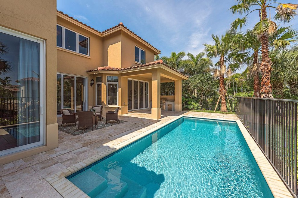 Diseño de piscina alargada clásica renovada grande rectangular en patio trasero con adoquines de piedra natural