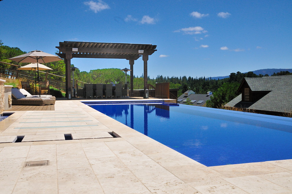 Idee per una grande piscina a sfioro infinito minimal rettangolare dietro casa con fontane e pavimentazioni in pietra naturale