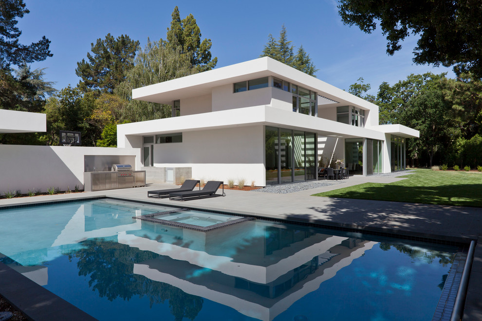 Foto di una grande piscina minimalista rettangolare dietro casa con una vasca idromassaggio e lastre di cemento