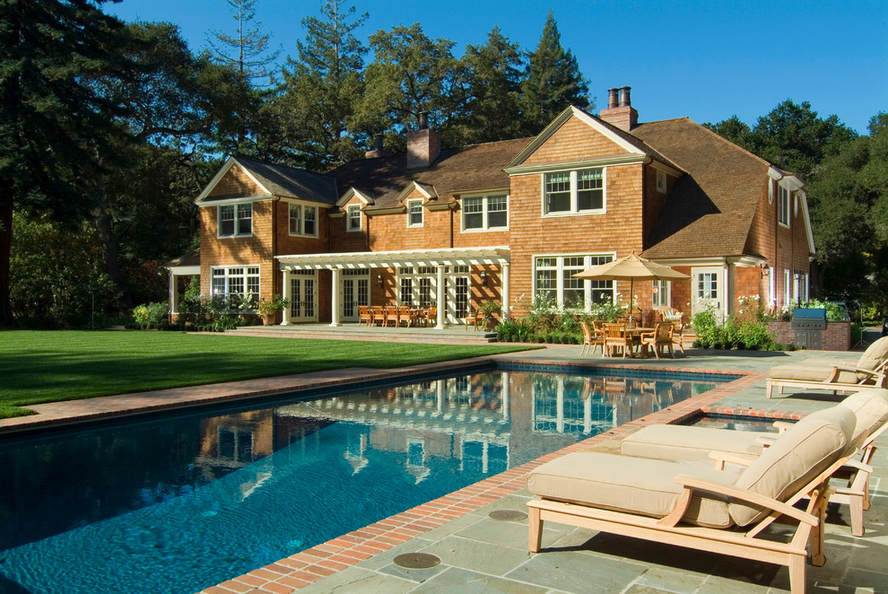 Diseño de piscina tradicional de tamaño medio rectangular en patio trasero con adoquines de ladrillo