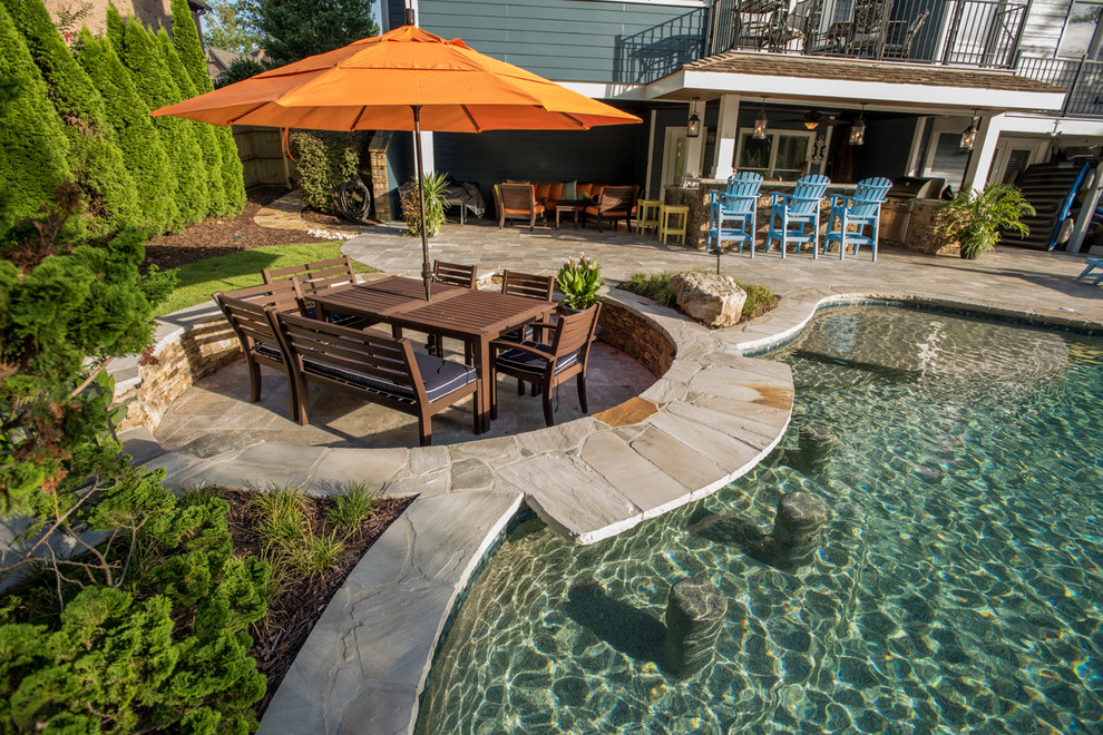 Foto de piscina con tobogán infinita tropical extra grande a medida en patio trasero con adoquines de piedra natural