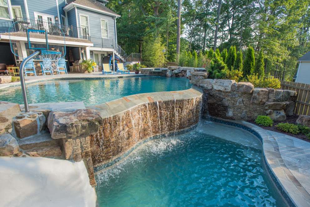 Ejemplo de piscina con tobogán infinita exótica extra grande a medida en patio trasero con adoquines de piedra natural