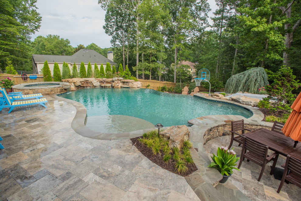 Foto de piscina con tobogán infinita tropical extra grande a medida en patio trasero con adoquines de piedra natural