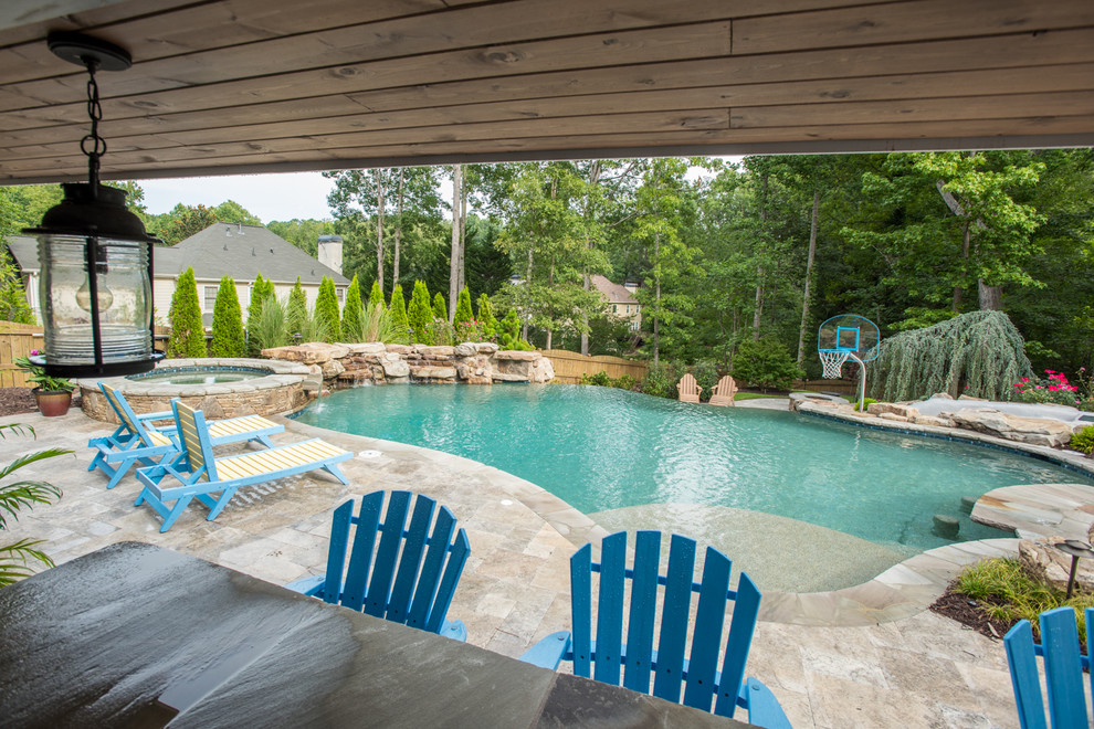 Ejemplo de piscina con tobogán infinita tropical extra grande a medida en patio trasero con adoquines de piedra natural