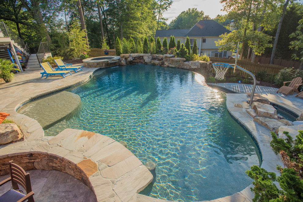 Modelo de piscina con tobogán infinita exótica extra grande a medida en patio trasero con adoquines de piedra natural