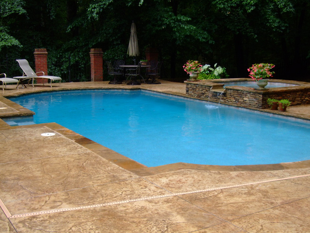 Immagine di una grande piscina classica rettangolare dietro casa con una vasca idromassaggio e lastre di cemento