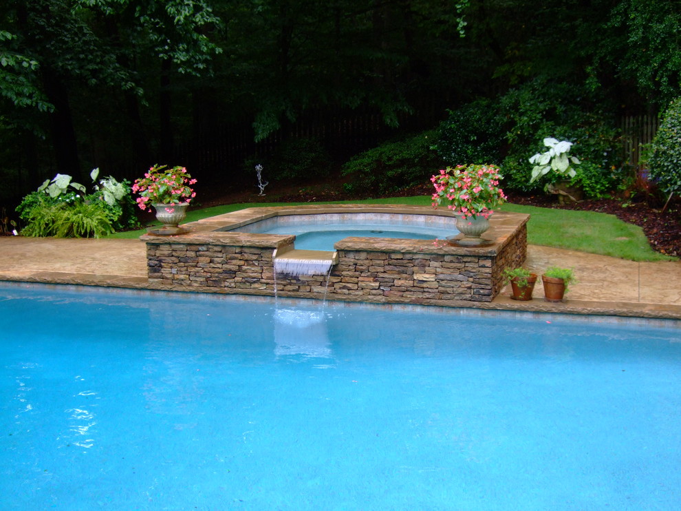 Foto de piscinas y jacuzzis tradicionales renovados grandes rectangulares en patio trasero con losas de hormigón