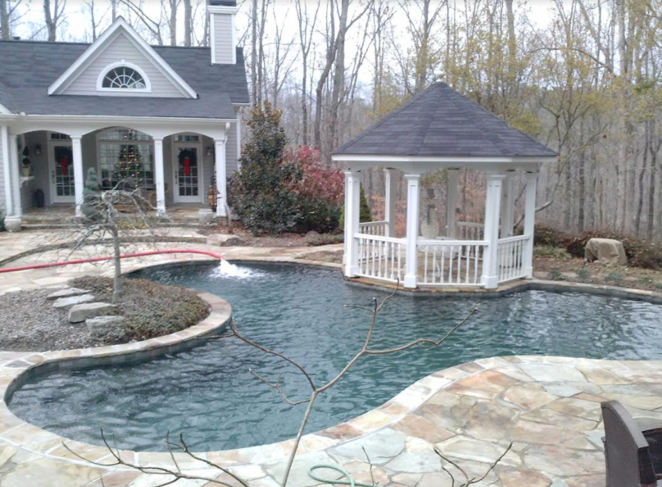 Imagen de piscina clásica renovada de tamaño medio a medida en patio trasero con adoquines de piedra natural