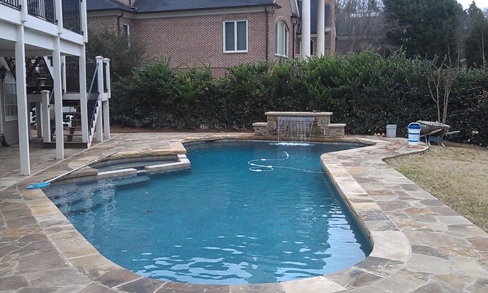 Ispirazione per una piscina classica personalizzata di medie dimensioni e dietro casa con una vasca idromassaggio e pavimentazioni in pietra naturale