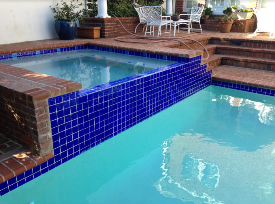 Modelo de piscinas y jacuzzis clásicos rectangulares en patio trasero con adoquines de ladrillo