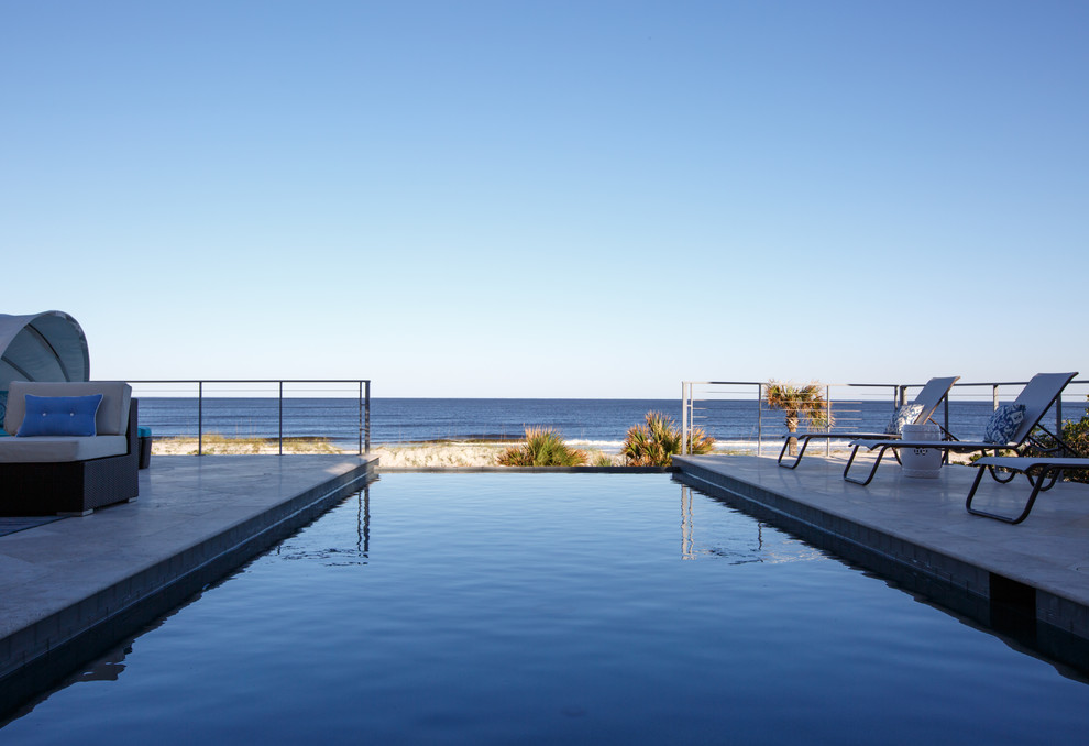 Foto de piscina infinita marinera grande rectangular en patio trasero con suelo de baldosas