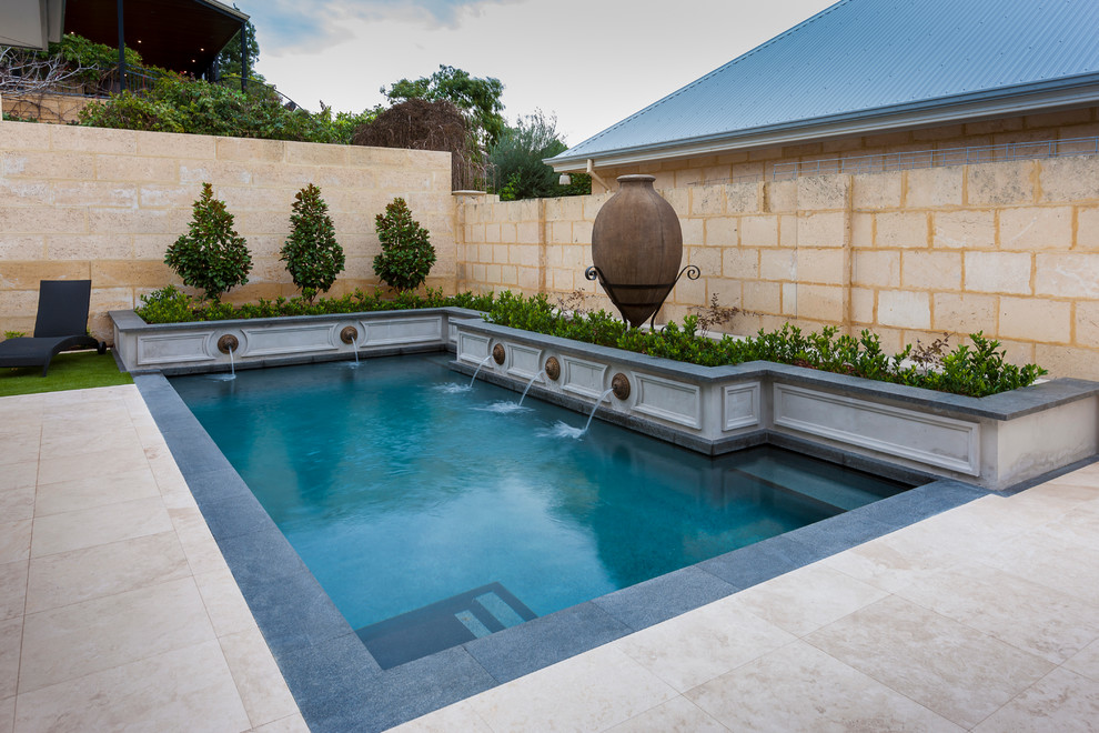 Diseño de piscina con fuente clásica grande rectangular en patio trasero con suelo de baldosas