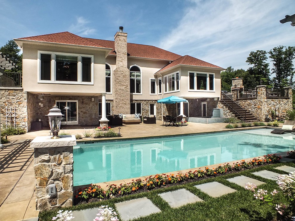 Immagine di una grande piscina design rettangolare dietro casa con pavimentazioni in cemento