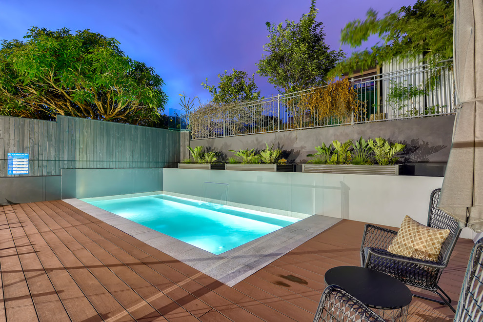 Foto de piscina con fuente elevada actual pequeña rectangular en patio trasero con entablado