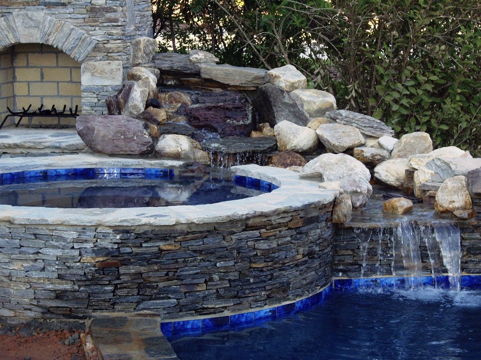 Immagine di una piscina naturale tradizionale rotonda dietro casa con una vasca idromassaggio e pavimentazioni in pietra naturale