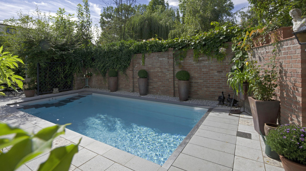 Ejemplo de piscina elevada mediterránea grande a medida en patio trasero con losas de hormigón