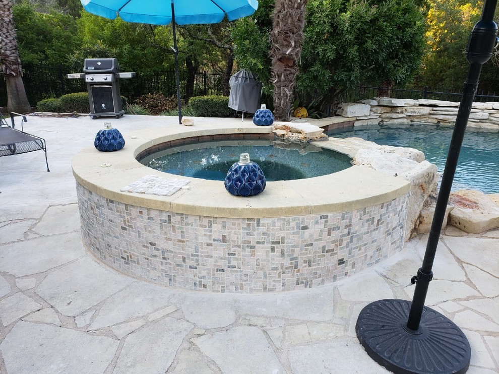 Modelo de piscinas y jacuzzis elevados minimalistas de tamaño medio redondeados en patio trasero con adoquines de piedra natural