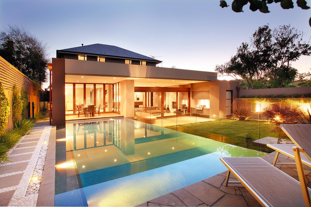 Moderner Infinity-Pool hinter dem Haus in rechteckiger Form mit Natursteinplatten in San Diego